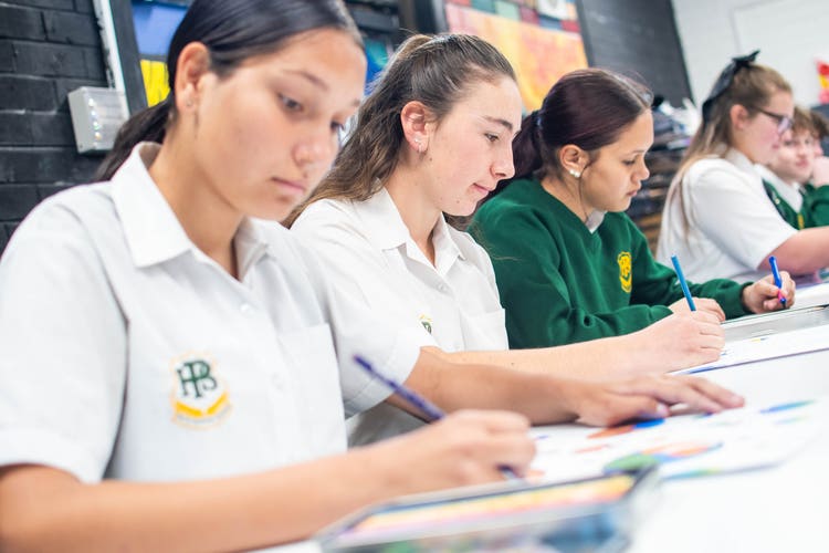 Photo shows four students working in a classroom.